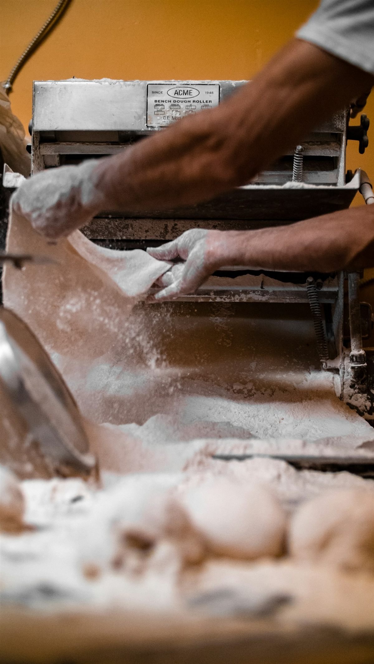Massa de pizza sendo aberta sobre a bancada